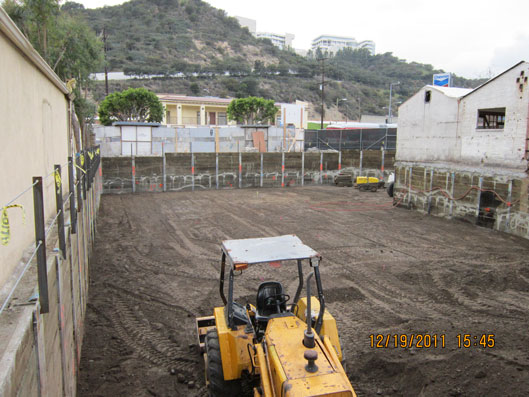 The project footprint was barely smaller than the space available. Shown is the excavation; the white structure is the original restaurant building. Photo (C) MATT Construction.