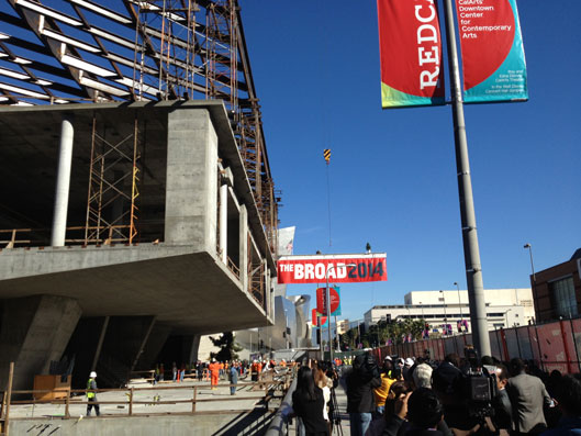 Draped with a commemorative banner, and topped with flag and tree, the ceremonial final steel beam is raised to the top of the Broad. A 294 ft construction crane was used to lift the 40 ft long, 1,700 pound beam. 